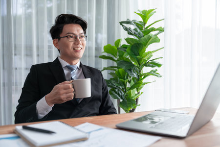Businessman working on laptop for on office desk workspace. Smart executive researching financial business data or planning strategic business marketing with computer on table. Jubilantの写真素材