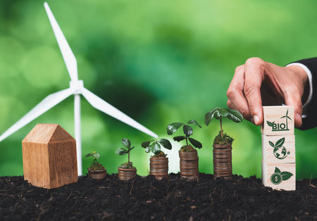 Businessman holding Bio energy symbol with seedling on coin stack and wind turbine. Corporate responsibility and Bio technology for sustainable energy and reducing pollution and CO2 emission. Alterの写真素材