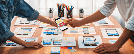 Panorama shot of front-end developer team brainstorming UI and UX designs for mobile app on paper wireframe interface. User interface development team planning for user-friendly UI design. Scrutinizeの写真素材