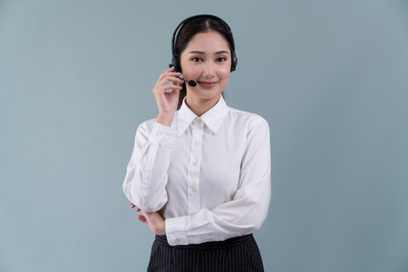 Attractive asian female call center operator with happy smile face advertises job opportunity on empty space, wearing a formal suit and headset on customizable isolated background. Enthusiasticの写真素材