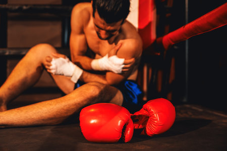 Caucasian boxer with pain and injury after intense boxing training or fighting match, sitting at the edge of ring. Physical injury in sport concept. Impetusの写真素材