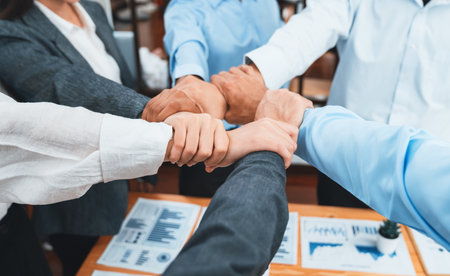 Diverse team of officer workers hold hands in circle, showing solidarity and teamwork in corporate...