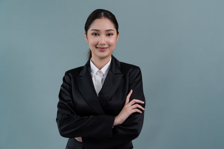 Confident young businesswoman stands on isolated background, posing in formal black suit. Office lady or manager with smart and professional appearance. Enthusiasticの写真素材