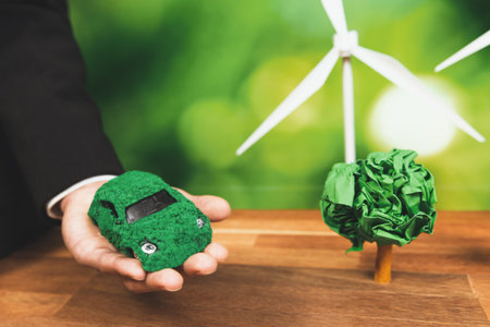 Businessman holding green eco car model in office. Electric vehicle utilized by eco-friendly business for environmental friendly transportation. Corporate responsible with zero CO2 emission. Alterの写真素材