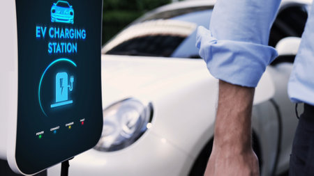 Businessman recharge his electric car from charging station at city center or public car park. Eco friendly rechargeable car using alternative clean energy in urban city lifestyle.Peruseの写真素材