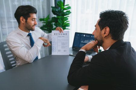 Interviewing job applicant in office with resume paper. Candidate wear suit for formal conversation with interviewer. Recruitment process with question about career and work experience. Ferventの写真素材