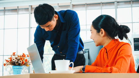 Two business people talk project strategy at office meeting room. Businessman discuss project planning with colleague at modern workplace while having conversation and advice on financial report. Jivyの写真素材
