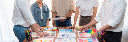 Graphic designer brainstorm logo and graphic art at busy creative studio workshop. Experiment and brainstorm color palette and pattern at workspace table for creative design. Panorama shot. Scrutinizeの写真素材