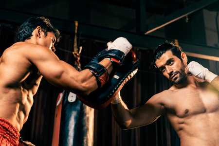 Asian and Caucasian Muay Thai boxer unleash upper cut punch attack in fierce boxing training session, deliver punch strike to sparring trainer, showcasing Muay Thai boxing technique and skill. Impetusの写真素材