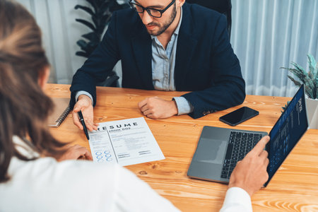 Job candidate engaging conversation with interviewer during job interview. Job applicant present work experience and qualification by digital resume on laptop and CV paper to HR manager. Entityの写真素材