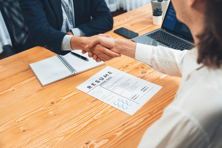 After successful meeting or job interview, two happy businessmen shake hands over resume papers. HR manager extend hand for congratulatory handshake to job applicant, welcoming new employee. Entityの写真素材