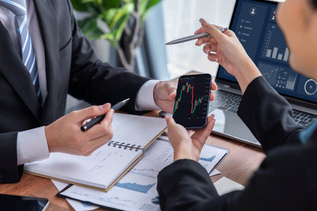 Risk management or financial team working and analyzing on clients portfolio while monitoring stock graphs on smartphone screen. Stock investment company with data analysis in office. Jubilantの写真素材