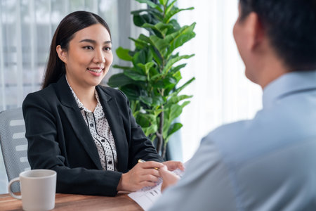 Conversational job interview between interviewer and candidate. HR manager asking about candidate qualifications and application for job position with resume. Job employment for applicant. Jubilantの写真素材