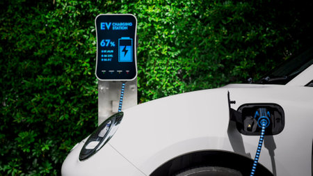 Electric car plugged in with charging station to recharge battery with electricity by EV charger...