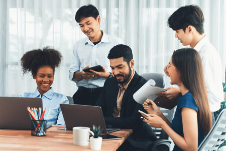 Happy diverse business people work together, discussing in corporate office. Professional and diversity teamwork discuss business plan on desk with laptop. Modern multicultural office worker. Concordの写真素材