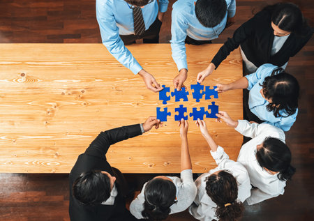 Multiethnic business people holding jigsaw pieces and merge them together as effective solution solving teamwork, shared vision and common goal combining diverse talent. Panorama top view. Meticulousの写真素材