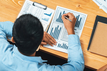 Top view diverse group of business analyst team analyzing financial data report paper on meeting table. Chart and graph dashboard by business intelligence analysis. Meticulousの写真素材