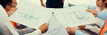 Engineer partner drawing and working on blueprint design together on office table for architectural...