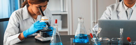 Group of dedicated scientist conduct chemical experiment using microscope in medical laboratory to...