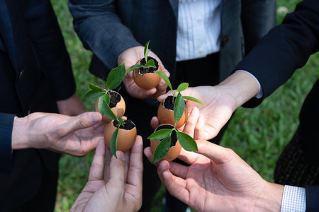 Group of business people holding repuposed eggshell transformed into fertilizer pot, symbolizing...