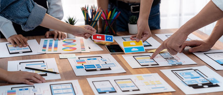 Panorama shot of front-end developer team brainstorming UI and UX designs for mobile app on paper wireframe interface. User interface development team planning for user-friendly UI design. Scrutinizeの写真素材