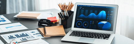 Data analysis dashboard display on laptop screen on office table with financial papers by Fintech BI technology for business marketing and strategy in corporate meeting room. Insightの写真素材