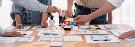 Panorama shot of front-end developer team brainstorming UI and UX designs for mobile app on paper wireframe interface. User interface development team planning for user-friendly UI design. Scrutinizeの写真素材