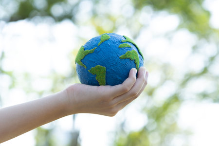 Young boys hand holding planet Earth globe at natural park background as Earth day to save this planet with ESG principle and environment friendly energy for brighter future. Gyreの写真素材