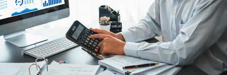 Corporate auditor calculating budget with calculator on his office desk. Dedicated accountant professional of accounting business company analyzing financial document to forecast income. Insightの写真素材