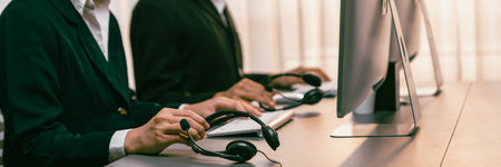 Panorama focus hand holding headset on call center workspace desk with blur background of operator...