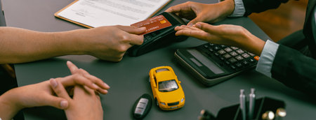 Customer client purchases new car with credit card via electronic terminal after finishing the deal with car dealer. Smooth car ownership transfer with secure electronic digital payment. Prodigyの写真素材