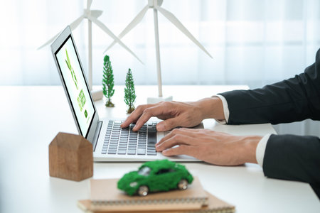 Businessman working in office developing plan or business project on eco-friendly ev car using net zero alternative energy technology on computer for greener environment as apart of CSR effort. Gyreの写真素材