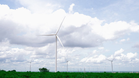 Progressive way of utilizing wind as renewable source of energy to power the modern way of life by wind turbine farm on green field or hill. Windmill generator generate electric with no CO2 emission.の写真素材