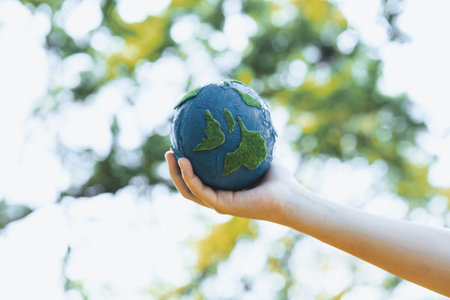 Young boys hand holding planet Earth globe at natural park background as Earth day to save this planet with ESG principle and environment friendly energy for brighter future. Gyreの写真素材