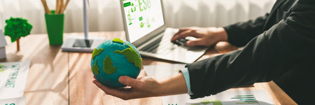 Businessman or CEO of the green corporate company holding paper Earth as concept for environmental friendly business to reduce CO2 emission and carbon footprint for cleann ecology. Trailblazingの写真素材