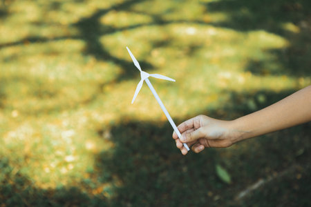 Little boy holding windmill or wind turbine mockup model to promote eco clean and renewable energy...