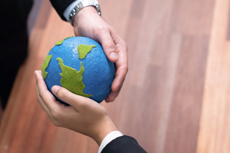 Top view business people holding Earth together in synergy as team building to utilize eco...
