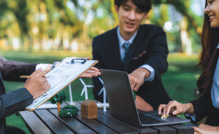 Group of asian business people presenting environmentally friendly development plan and sustainable technology project for greener future, establishing outdoor eco business office at natural park.Gyreの写真素材