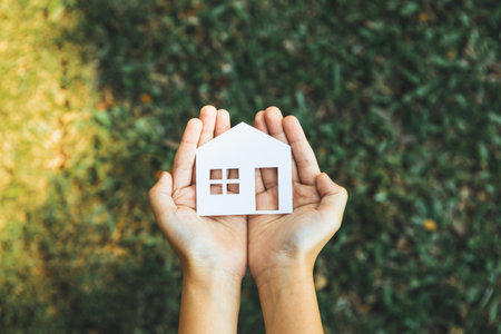 Top view hand hold house icon, presenting house loan opportunity as part of real estate sales. Promoting eco-smart homes, embodying vision for sustainable bright future nurturing with nature. Gyreの写真素材