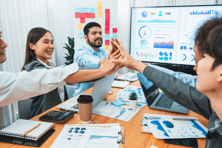 Diverse business team celebrate successful meeting with high-fives and expressions of happiness in...