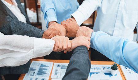 Diverse team of officer workers hold hands in circle, showing solidarity and teamwork in corporate office. Businesspeople form strong community built on integrity and collaboration. Concordの写真素材