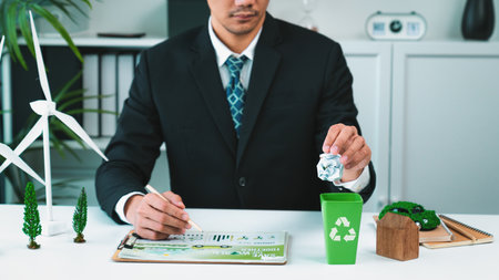 Businessman put paper waste on small tiny recycle bin in his office symbolize corporate effort on eco-friendly waste management by recycling for greener environment and zero pollution. Gyreの写真素材