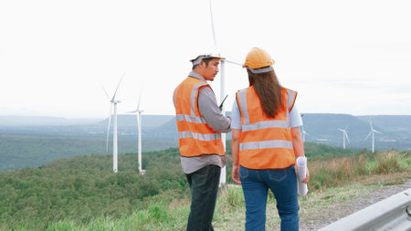 Male and female engineers working on a wind farm atop a hill or mountain in the rural. Progressive ideal for the future production of renewable, sustainable energy.の写真素材