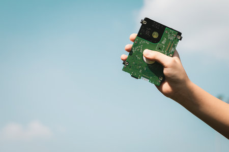 Recyclable electric waste held in hand up on sky background. Hand holding electronic trash for recycle reduce and reuse concept to promote clean environment with recycling management. Gyreの写真素材