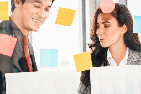 Business people work on project planning board in office and having conversation with coworker friend to analyze project development . They use sticky notes posted on glass to make it organized. Jivyの写真素材