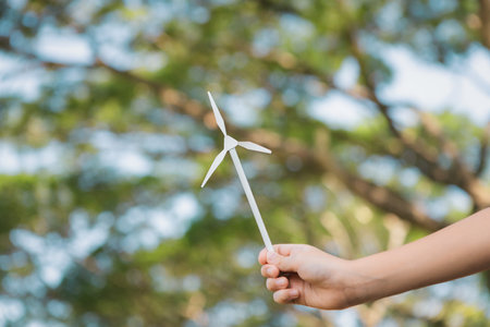 Little boy holding windmill or wind turbine mockup model to promote eco clean and renewable energy technology utilization for future generation and sustainable Earth. Gyreの写真素材