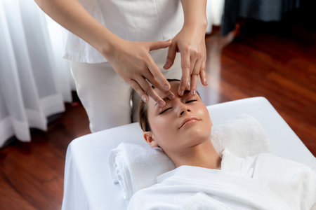 Caucasian woman enjoying relaxing anti-stress head massage and pampering facial beauty skin recreation leisure in dayspa modern light ambient at luxury resort or hotel spa salon. Quiescentの写真素材
