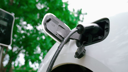 Progressive man install power cable plug to his electric vehicle, EV car from home charging station....