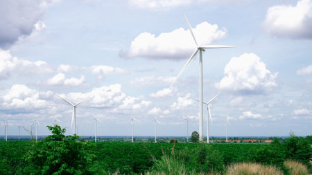 Progressive way of utilizing wind as renewable source of energy to power the modern way of life by wind turbine farm on green field or hill. Windmill generator generate electric with no CO2 emission.の写真素材