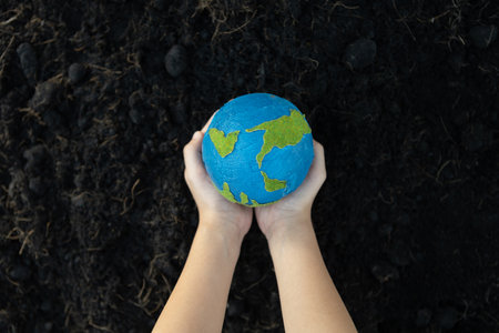 Young boys hand holding planet Earth globe on fertile soil background as Earth day to save this planet with ESG principle and environment friendly energy for brighter future. Gyreの写真素材